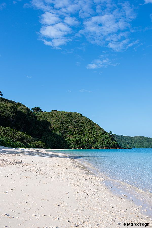 Vista panoramica della spiaggia di Ida, situata sull'isola di Iriomote a Okinawa, con sabbia bianca e vegetazione.