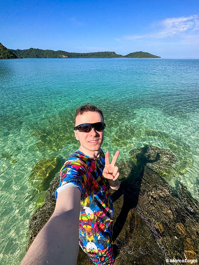 Marco Togni sulla spiaggia di Ida a Iriomote, con maglietta colorata e mare cristallino