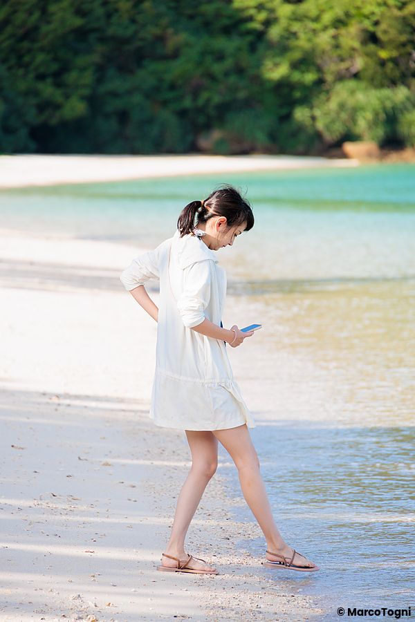 Giovane donna in spiaggia a Iriomote, Okinawa, cammina nell'acqua.
