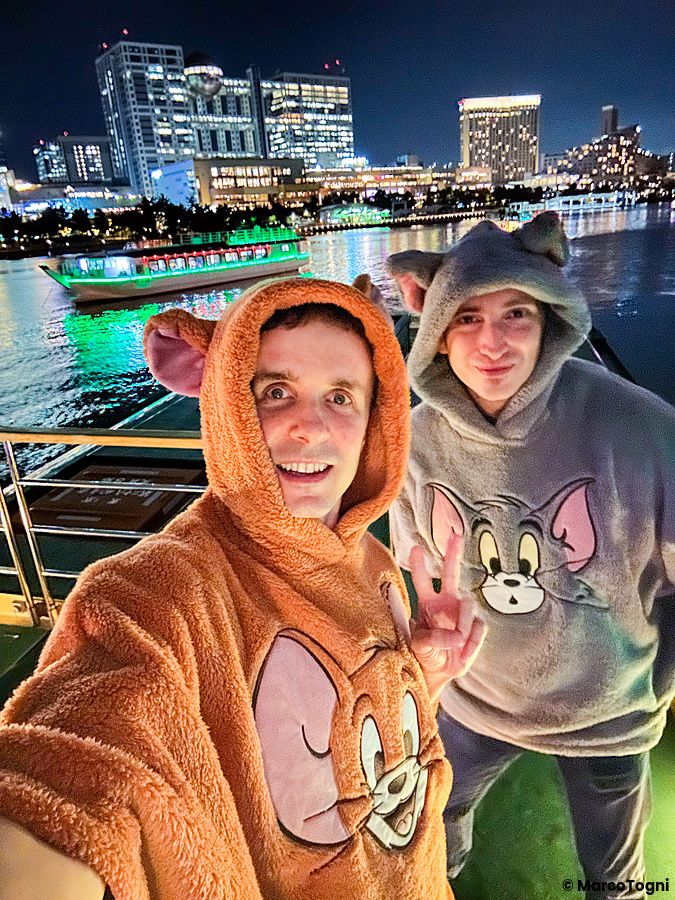 Marco Togni con felpa di Tom e Jerry sorride a bordo di una Yakatabune a Tokyo durante una crociera notturna.