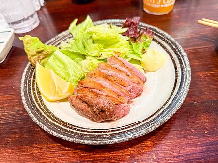 Una porzione di anatra a Gion Yuki servita con lattuga e limone su un piatto di ceramica.