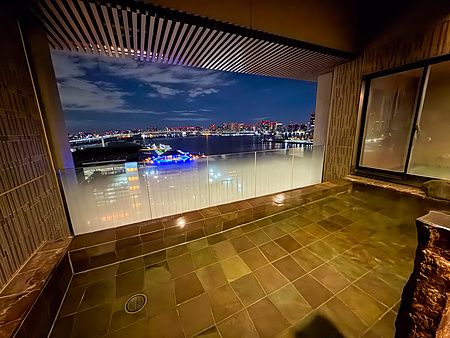 Bagno pubblico con acqua termale onsen a La Vista Tokyo Bay con vista notturna sulla baia di Tokyo.