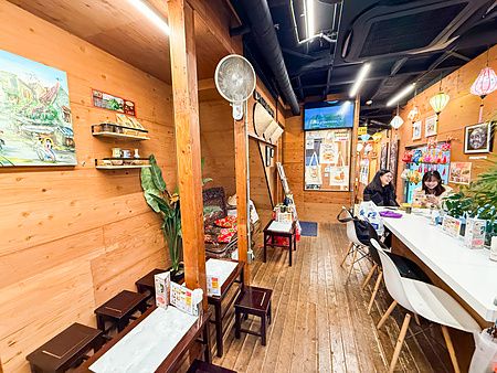 Interno del Café Giang a Yokohama con pareti in legno, lanterne decorative e persone sedute al bancone.