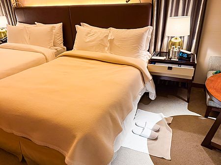 Veduta di una stanza in ordine durante il turndown service a The St. Regis Osaka con letti rifatti e ciabatte pronte.
