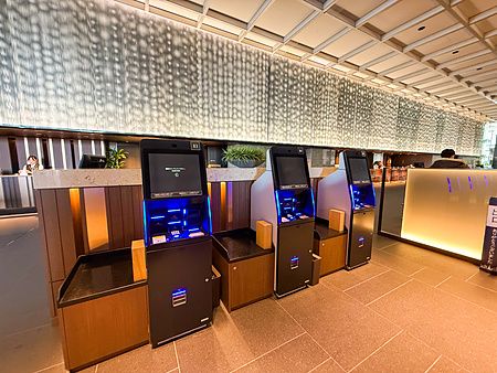 Tre terminali per il check-out automatico a La Vista Tokyo Bay allineati in una hall moderna a Tokyo.