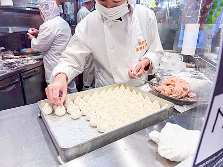 Uno chef prepara a mano dim sum su una teglia all'interno di un ristorante nella Chinatown di Yokohama.
