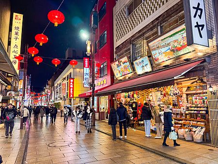 Veduta serale di una strada pedonale nella Chinatown di Yokohama, affollata di persone tra lanterne rosse e negozi.
