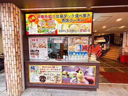 Esterno di Chukagai Daihanten con vetrina e cartellonistica per il cibo d'asporto nella Chinatown di Yokohama.