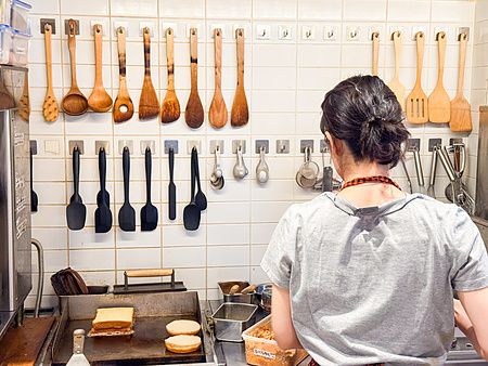 Una persona prepara del pane su una piastra all'interno della cucina a RoJean, un caffè di Tokyo.