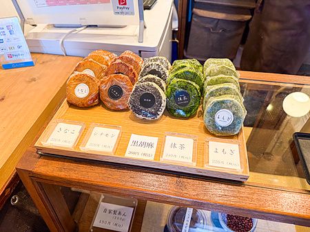 Dolcetti vari a Hakata Hiiragi Taiyaki disposti su un espositore in legno con etichette di prezzo in un negozio a Fukuoka.
