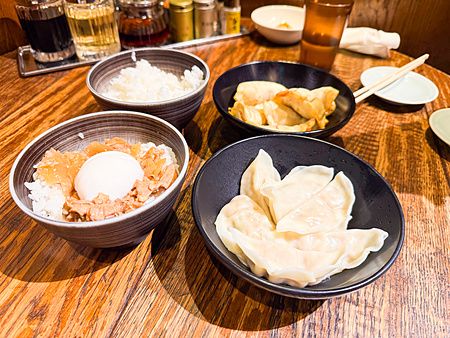 Piatti di gyoza e ciotole di riso serviti su un tavolo di legno presso il ristorante Gyoza no Fukuho a Tokyo.