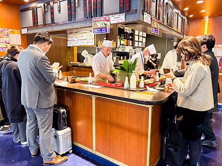 Interno del ristorante di sushi Matakoiya presso il Terminal 1 dell'aeroporto di Haneda con chef e clienti.