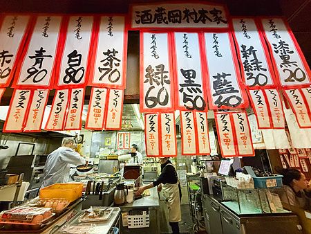 Veduta dell'interno a Gion Yuki con persone che lavorano dietro il bancone sotto numerose insegne di carta rossa e bianca.