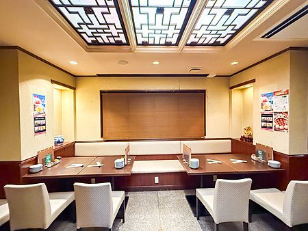 L'interno a Wangfujing nella Chinatown di Yokohama mostra tavoli disposti simmetricamente con sedie chiare e pareti beige.