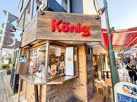L'insegna in legno con la scritta König sovrasta la vetrina di un piccolo ristorante specializzato in wurstel.
