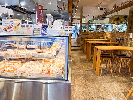 Interno del negozio e ristorante König a Kichijoji con bancone refrigerato pieno di wurstel e tavoli in legno.