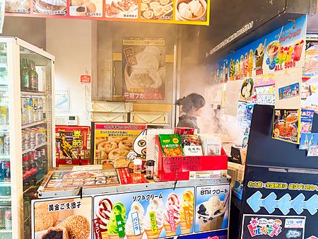 Interno del negozio Koseiwa a Yokohama con cartelli di cibo e una persona al lavoro dietro il bancone.