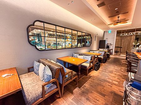 L'interno a Lotus Palace a Fukuoka presenta divanetti in legno e tavoli lungo una parete con un grande specchio a riquadri.