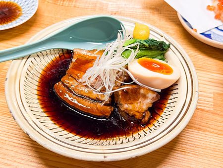 Un piatto di maiale a Hatonoyu con uovo marinato, verdure e salsa scura servito in un izakaya a Tokyo.