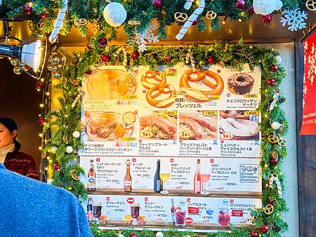 Un pannello menu natalizio con cibo tedesco e ghirlande decorative presso Azabudai Hills a Tokyo.