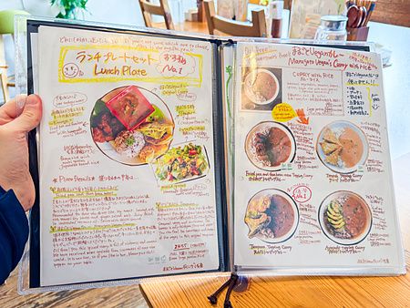 Menu plastificato e illustrato a mano del ristorante Marugoto Vegan Dining ad Asakusa con foto e descrizioni dei piatti.