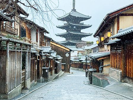 Veduta della Pagoda Yasaka a Kyoto durante una nevicata invernale, con strade e tetti coperti di neve.