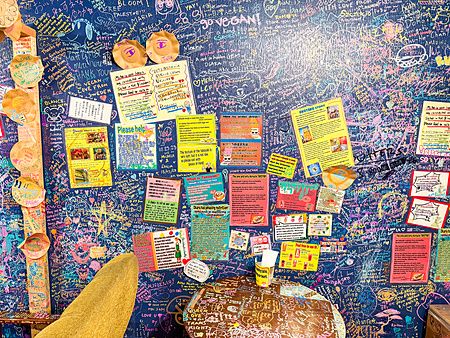 Parete blu del ristorante vegano e gluten free OKO a Osaka, interamente coperta da scritte e messaggi dei clienti.