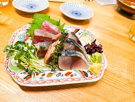 Sashimi assortito servito in un piatto decorato presso l'izakaya Hatonoyu a Tokyo.
