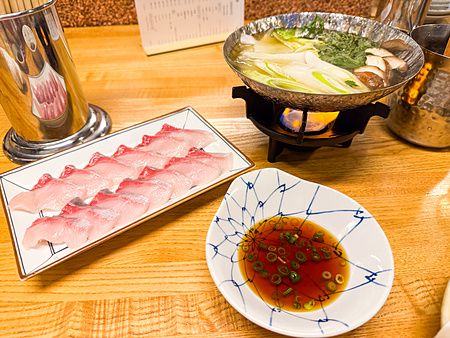Sashimi shabu shabu servito presso l'izakaya Hatonoyu a Tokyo, con pesce crudo, brodo caldo e salsa ponzu.