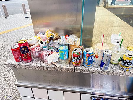 Rifiuti e lattine vuote abbandonate su un muretto esterno in pietra nel quartiere di Shibuya a Tokyo.
