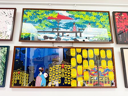 Una parete di un negozio Eirakuya a Kyoto con tenugui incorniciati che mostrano illustrazioni tradizionali giapponesi.