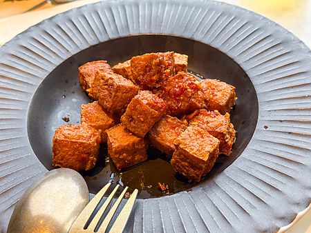 Un piatto di tofu piccante, piatto vegano a Lotus Palace, servito in una ciotola di ceramica scura a Fukuoka.