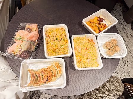 Diverse vaschette di cibo cinese d'asporto a Wangfujing poggiate su un tavolo circolare scuro a Yokohama.