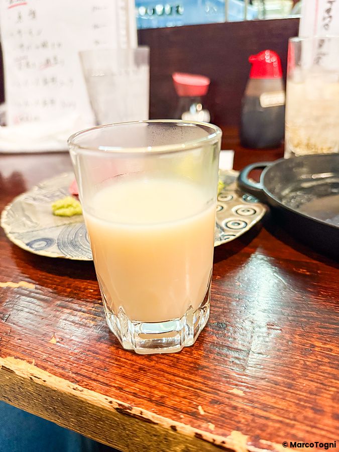 Un bicchiere di amazake su un tavolo di legno all'interno dell'izakaya Gion Yuki a Kyoto.