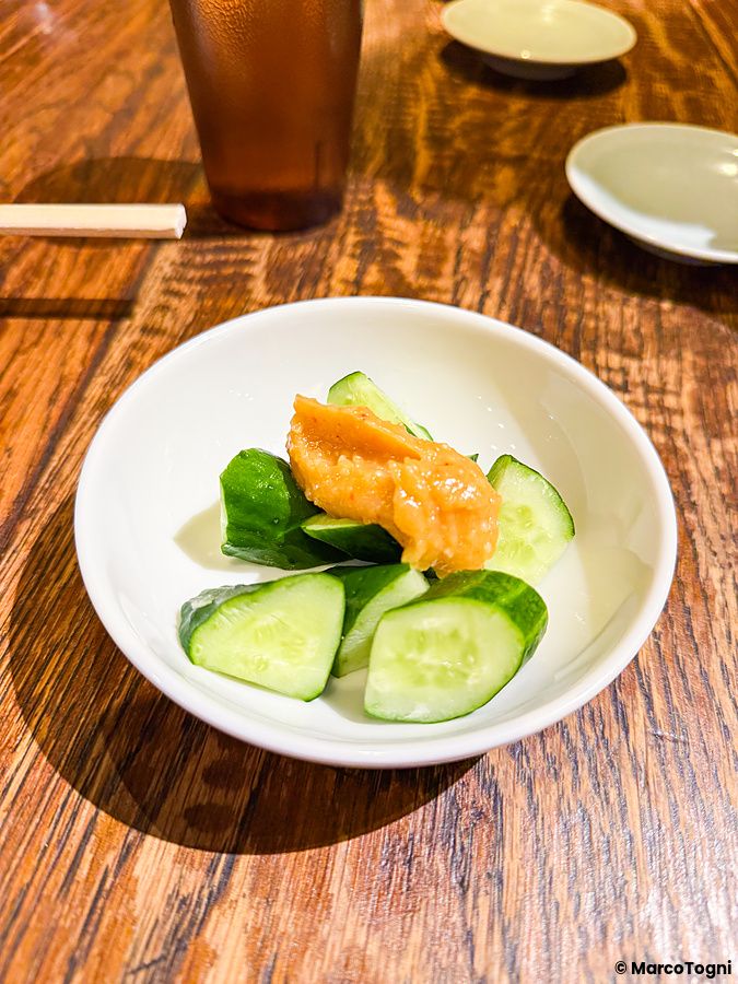Fette di cetrioli con salsa in una ciotolina bianca su un tavolo di legno al ristorante Gyoza no Fukuho a Tokyo.