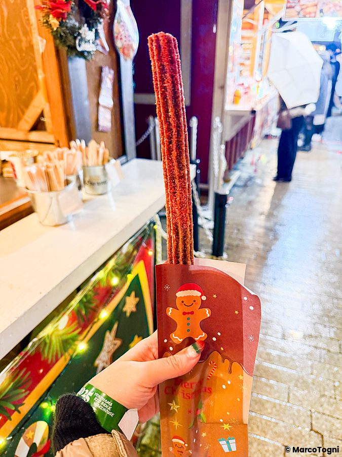 Una mano tiene un churros in un cartoccio natalizio allo Yokohama Red Brick Christmas Market.