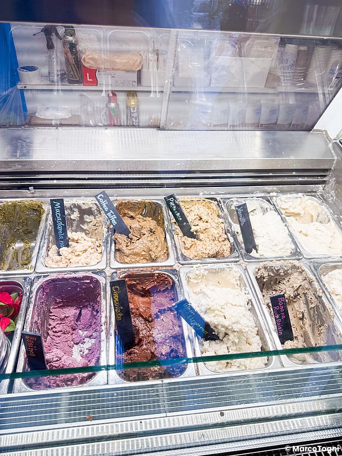 Vetrina refrigerata di Coconut Glens con vaschette di gelato vegano dai vari gusti e cartellini identificativi neri.