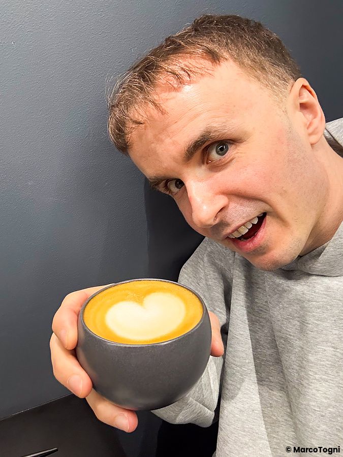 Marco Togni mostra una tazza di cappuccino con latte art a forma di cuore all'interno di X coffee a Ginza.