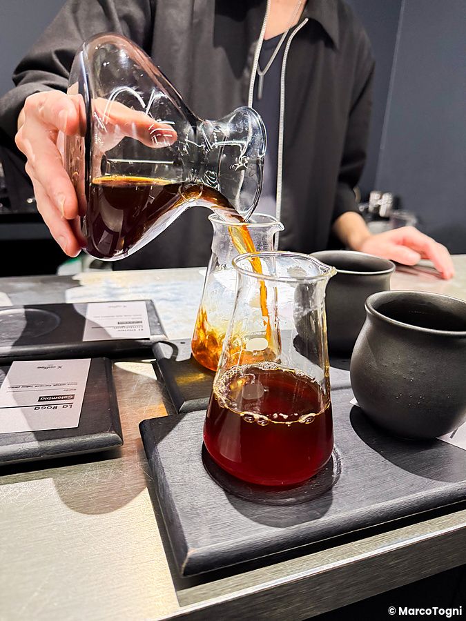 Un individuo versa caffè da un decanter in vetro in un contenitore da laboratorio presso la caffetteria X coffee a Ginza.
