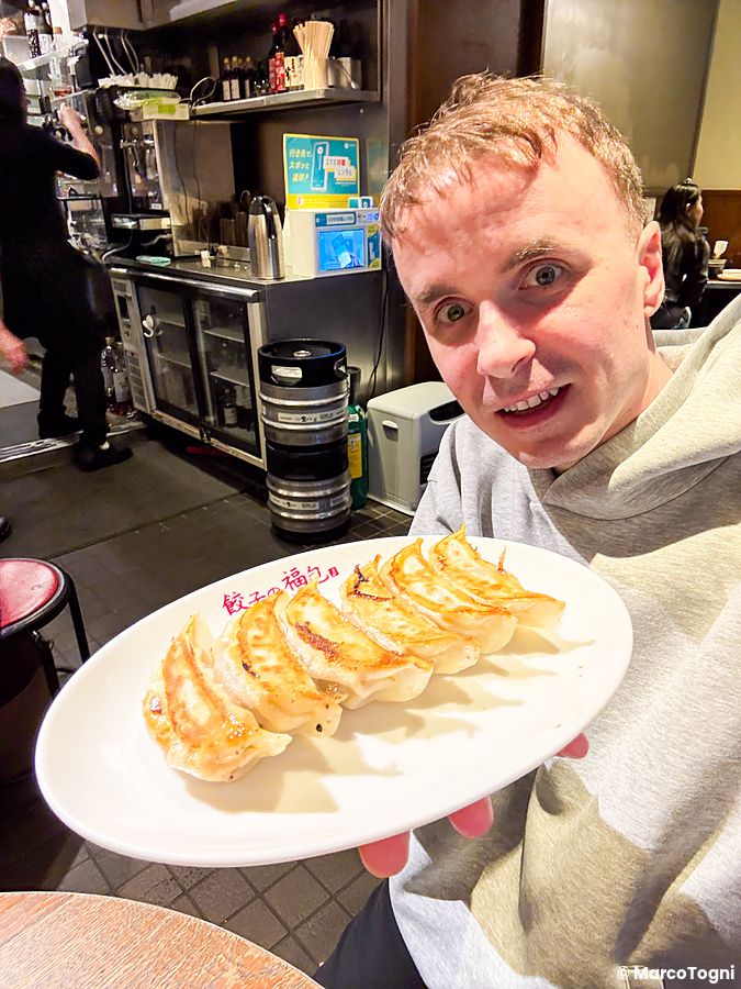 Marco Togni tiene un piatto di gyoza alla piastra a Gyoza no Fukuho in un ristorante di Tokyo.