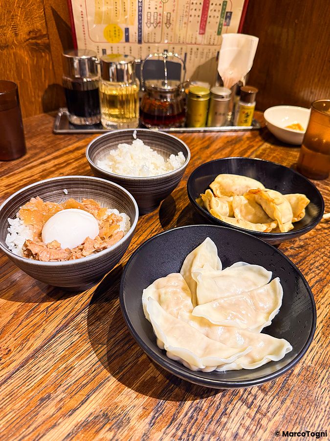 Diverse ciotole con gyoza e riso su un tavolo di legno all'interno del ristorante Gyoza no Fukuho a Tokyo.