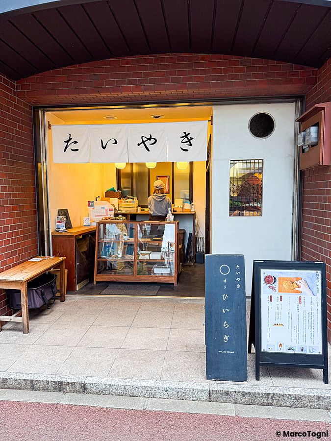 L'ingresso del negozio Hakata Hiiragi Taiyaki a Fukuoka con insegne in giapponese e una persona all'interno.