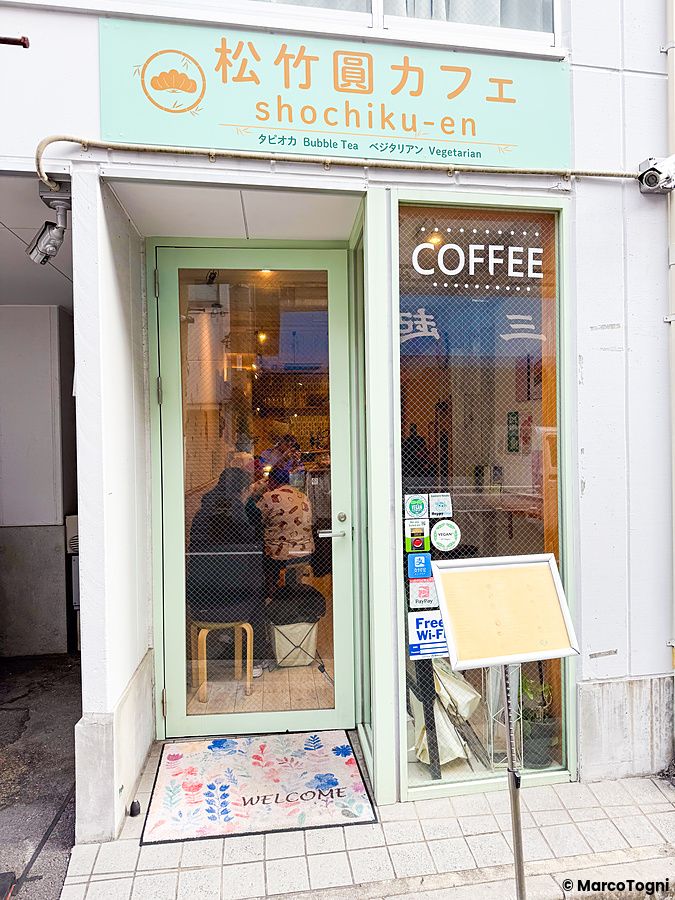 Ingresso del caffè vegano e gluten free Shochikuen ad Asakusa con porta a vetri e tappetino welcome.