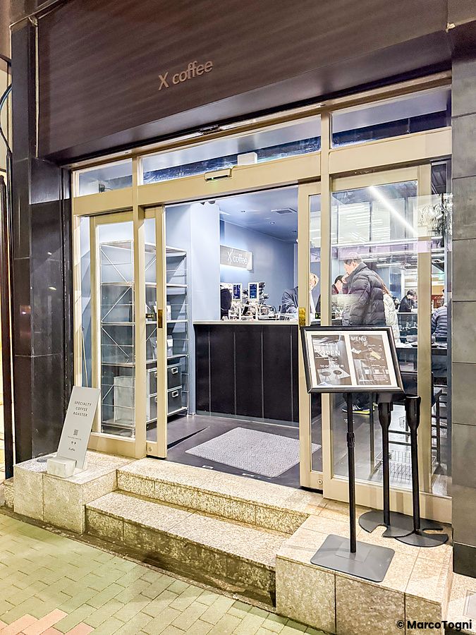 L'ingresso vetrato di X coffee a Ginza con persone visibili all'interno del locale.