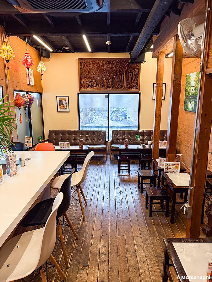 Interno a Café Giang, locale vietnamita a Yokohama con tavoli in legno, sedie moderne e decorazioni artigianali.
