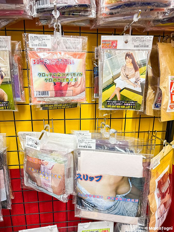 Confezioni di intimo usato in vendita appese a una griglia gialla all'interno di un sexy shop in Giappone.