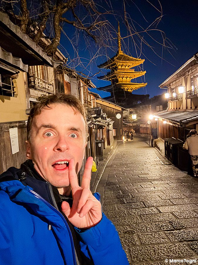 Marco Togni si scatta un selfie di sera con la pagoda Yasaka sullo sfondo, lungo una strada tradizionale a Kyoto.
