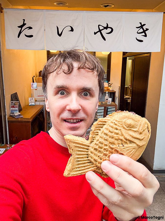 Marco Togni mostra un taiyaki davanti all'insegna del negozio Hakata Hiiragi Taiyaki a Fukuoka.