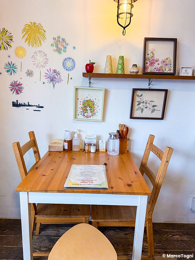 Interno del ristorante Marugoto Vegan Dining ad Asakusa con un tavolo di legno e decorazioni floreali sulla parete.
