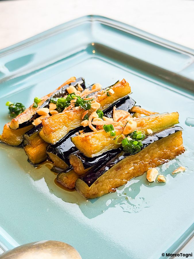 Piatto quadrato color carta da zucchero con melanzane, piatto vegano a Lotus Palace, guarnite con arachidi e erba cipollina.